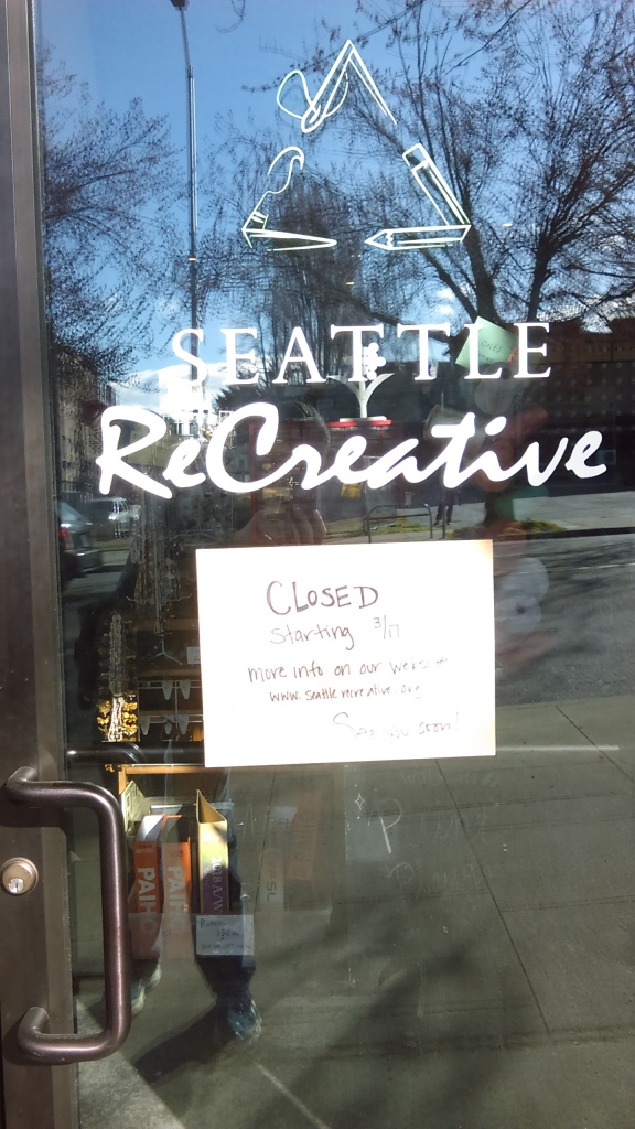 March 23, 2020, Greenwood, Seattle. On the door of Seattle ReCreative is a sign that says the store is closed. A legible closeup of the sign is in the image to the right.
